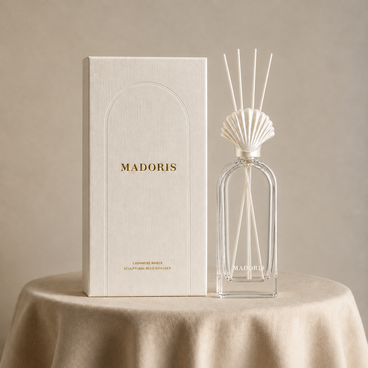 MADORIS Cashmere Amber reed diffuser and textured white gift box displayed on a warm beige draped surface