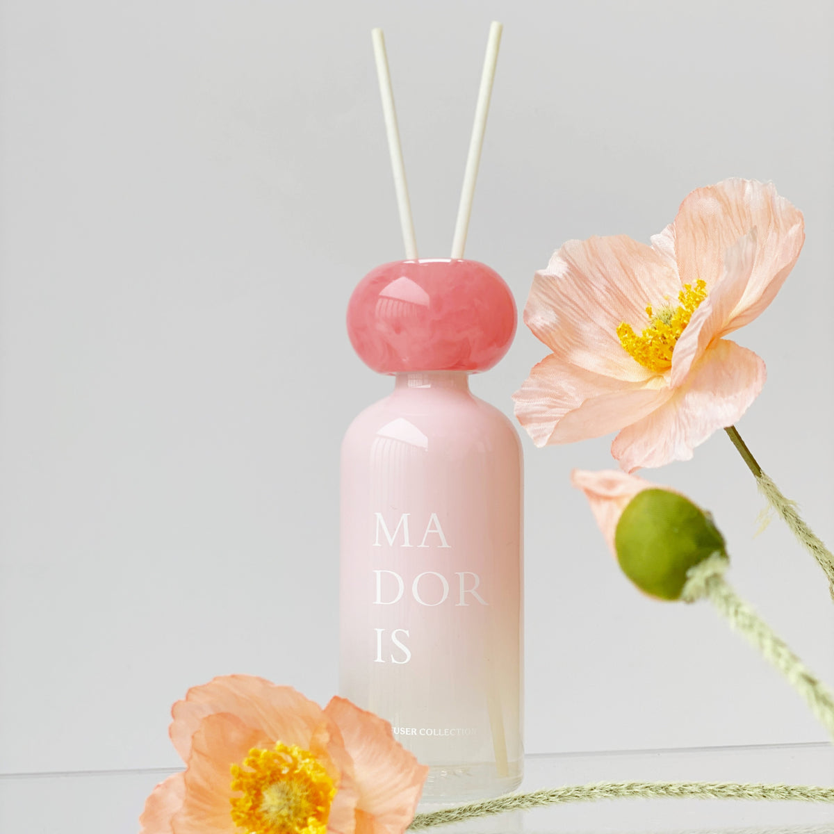 MADORIS Blush Veil reed diffuser styled with pink flowers and fresh fruit