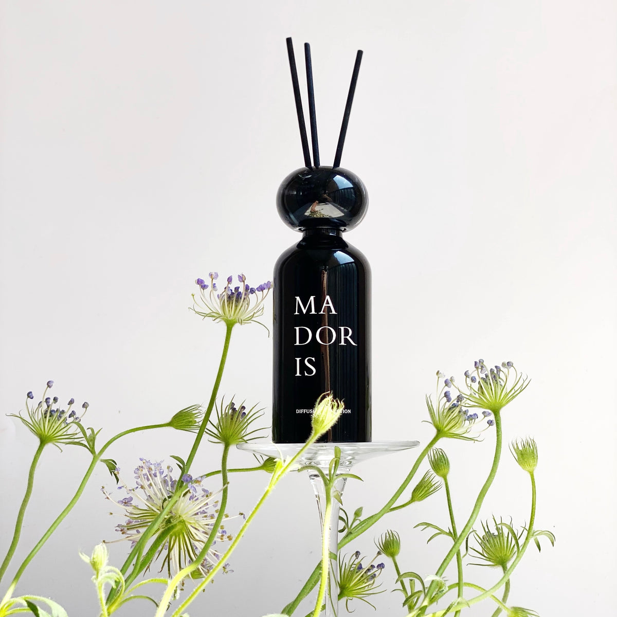 MADORIS Dark Citrus reed diffuser styled with fresh green botanicals and black reeds