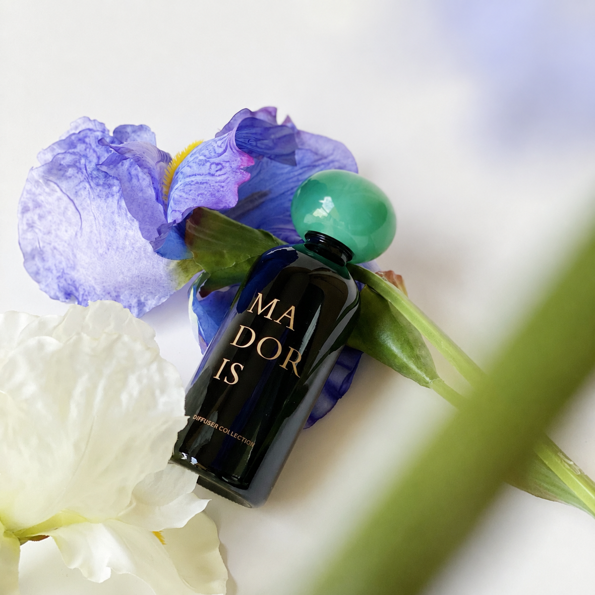 MADORIS Jade Mist reed diffuser styled with blue and purple flowers in a fresh botanical setting