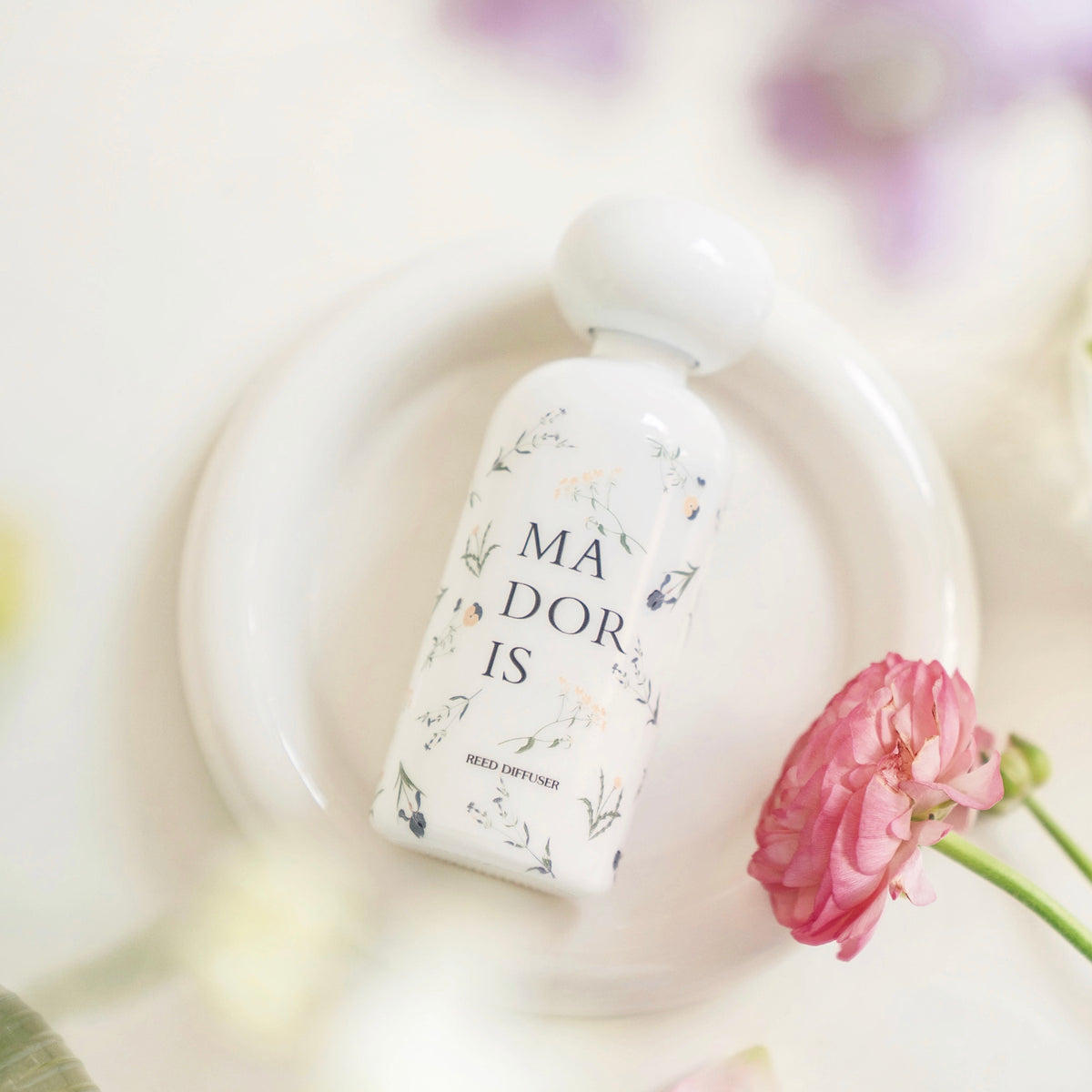 Close-up of MADORIS White Whisper reed diffuser with soft white and pink floral details