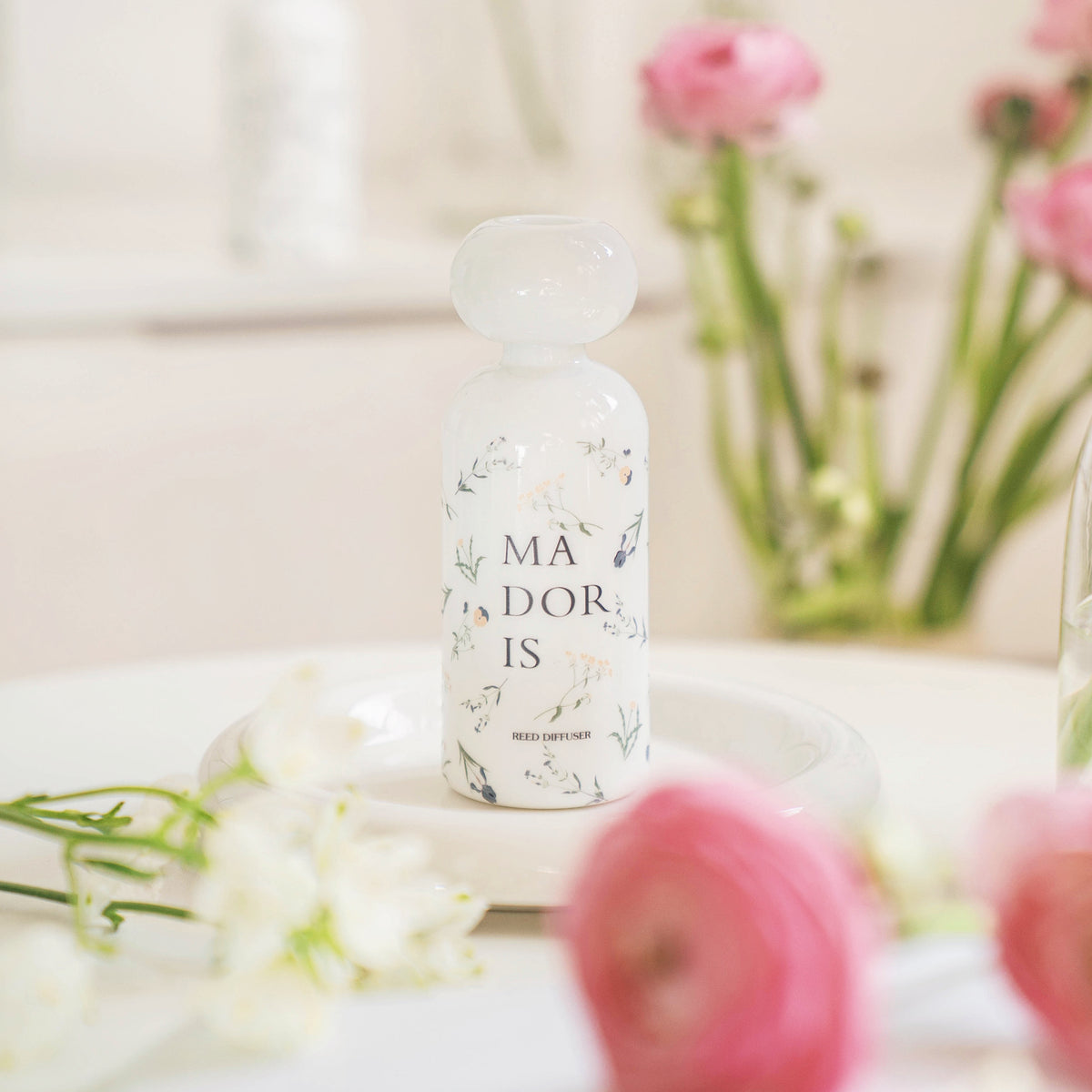 MADORIS White Whisper reed diffuser displayed with delicate flowers in a bright interior